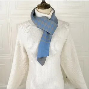 Detail of blue houndstooth knitted scarf with soft wool texture on white sweater
