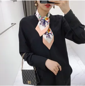 Close-up of silk-feel floral scarf tied as a bow over a chic black long-sleeve shirt