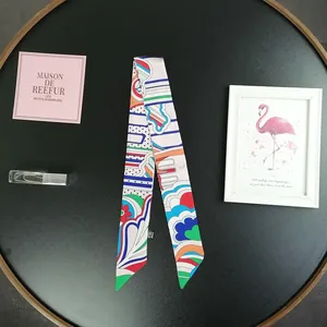 Sciarpa twilly in raso con motivi geometrici colorati su una superficie nera minimalista