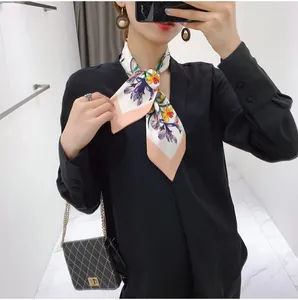 Detail of floral silk scarf styled with black V-neck top and quilted chain bag