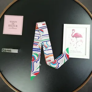 Dettaglio di un foulard in seta twilly stampato con motivi floreali su un vassoio