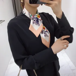 Close-up of a floral silk neck scarf tied on model with black V-neck shirt and ring