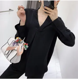 Detail of elegant black V-neck silk shirt with buttoned cuffs and matching floral scarf