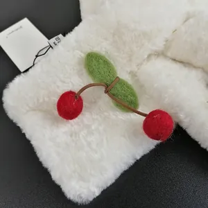 Dettaglio sciarpa in finta pelliccia bianca con ciliegia 3D ed etichetta di lavaggio