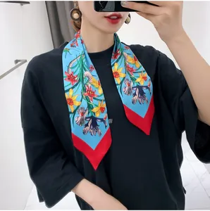 Detail view of a blue floral silk scarf worn on the neck over a black shirt