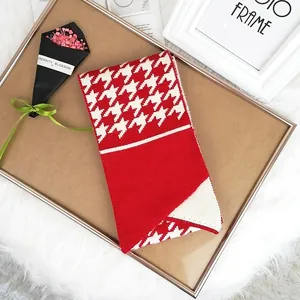 Red and white houndstooth knitted scarf with button detail on cozy wooden tray