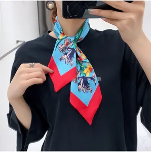 Close-up of floral print twilly silk scarf in light blue tied elegantly on neck