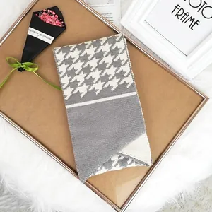 Knitted winter scarf with grey and white houndstooth pattern and button detail