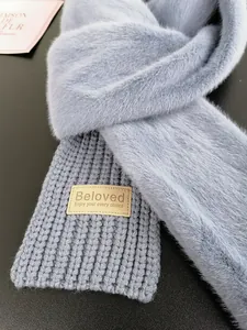 Detail of grey-blue knit scarf with faux fur trim and decorative leather label