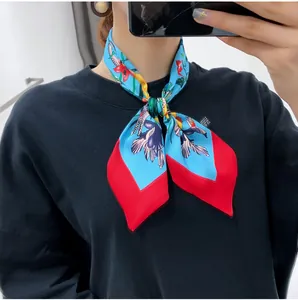 Detailed texture of silk floral scarf with vibrant red borders and blue botanical patterns