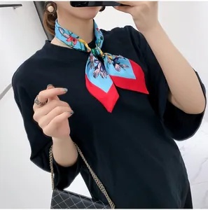 Close-up of silk scarf with floral and bird prints tied around the neck on a black tee