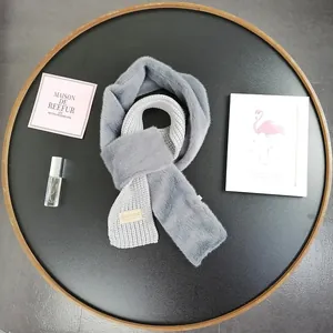 Detail of gray knit and faux fur scarf with Beloved leather patch on a stylized tray