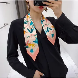 Close-up of floral silk twilly scarf with leopard print worn on a black V-neck top