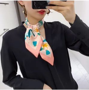 Close-up of a floral silk twilly scarf with cartoon animal print worn as a neck tie