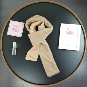 Close-up of khaki knit and faux fur scarf with 'Beloved' patch on a wooden tray