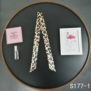 Macro detail of a leopard print silk scarf accessory with pointed ends for bag handles