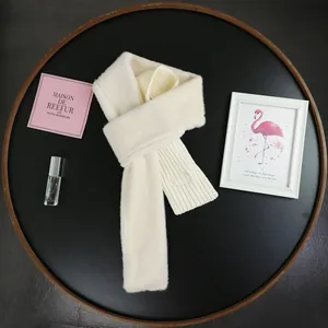 Detail of white faux fur knitted cross scarf on a black tray with elegant lifestyle props