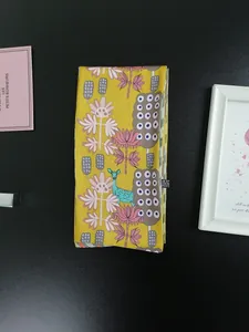 Detail of a yellow floral ribbon scarf featuring a teal deer pattern and pink flowers