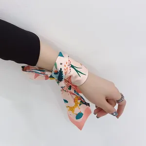 Wrist styling of a pink floral silk scarf featuring tropical leopard and leaf prints