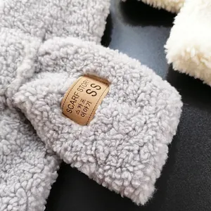 Thick grey faux lamb wool scarf with a brown leather label and soft texture