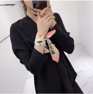 Floral silk scarf tied as a wrist accessory with leopard and tropical leaf patterns