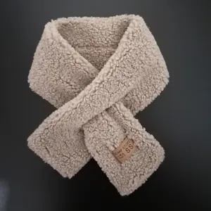 Detailed view of oatmeal faux lamb wool scarf texture and brown leather brand label