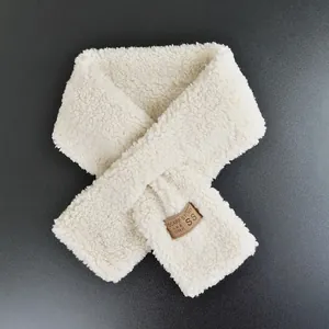 Detail of soft cream faux lamb wool scarf featuring a crossover design and leather label