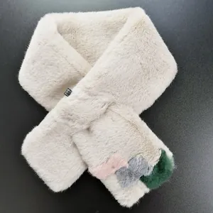 Detail of soft faux fur scarf with colorful plush pom-poms on grey background