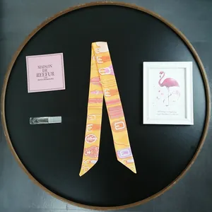 Detail of a warm-toned skinny silk scarf featuring elegant belt and buckle patterns