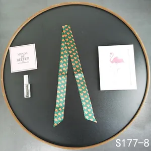 Detail of dark green skinny scarf with orange heart patterns for bag handles