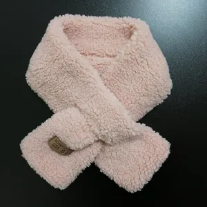 Detail of light pink fleece scarf with premium brown leather label and soft texture