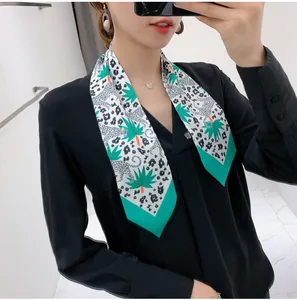 Detail of floral leopard print silk scarf tied around neck with green leaf pattern