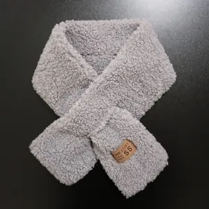 Macro detail of the light gray sherpa fleece texture and leather label on the scarf