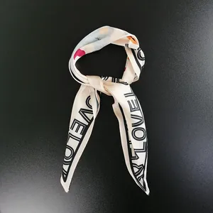 Close-up of beige silk scarf with black LOVE lettering print on matte background