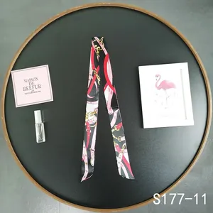 Detailed view of a slim black twilly scarf with elegant chain and belt patterns