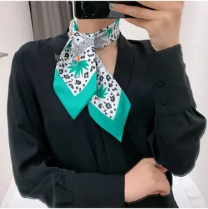 Close-up of leopard and palm leaf print silk scarf styled with a black shirt for a chic look