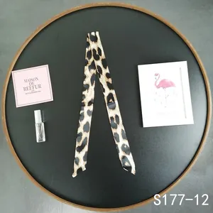 Detail showing leopard print silk scarf wrapped on a round tray for bag decoration