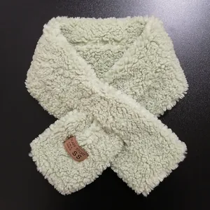 Detail of light green faux lamb wool scarf featuring a premium leather patch and soft texture