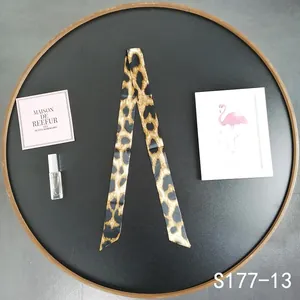 Macro view of leopard print satin scarf handle wrap for handbags with smooth silk texture