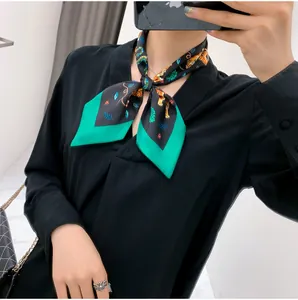 Close-up of silk-like scarf with tiger and floral patterns tied on a black V-neck shirt