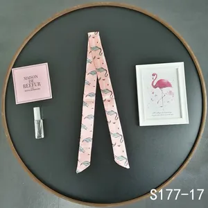 Macro view of pink long ribbon scarf with artistic flamingo print for bag handles