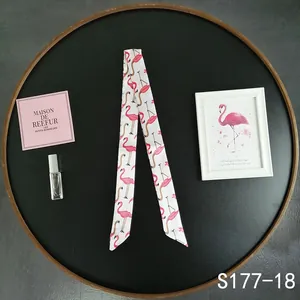 Detailed view of pink flamingo print twilly silk scarf tied on a tray accessory