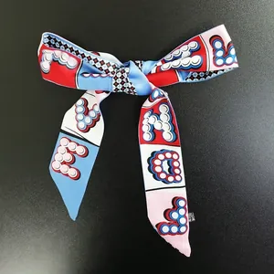 Dettaglio di un foulard sottile in seta a fiocco con motivi di lettere colorate
