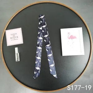 Detail of navy blue silk scarf with white flamingo print used as a bag handle wrap