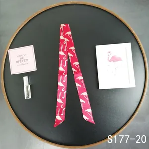 Detail of red flamingo print twilly silk scarf tied on a bag handle for decoration