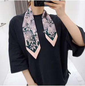 Detail of floral silk scarf with pink and green tiger palm pattern tied on the neck