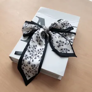 Détail d'un foulard en polyester effet soie avec motif feuilles et bordure noire