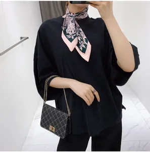 Detail of floral silk scarf with tiger print styled on a black cotton shirt with luxury bag