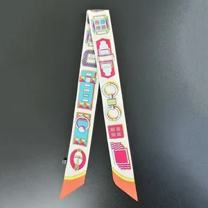 Detail of a beige twilly scarf with geometric patterns and a sewn-in wash label