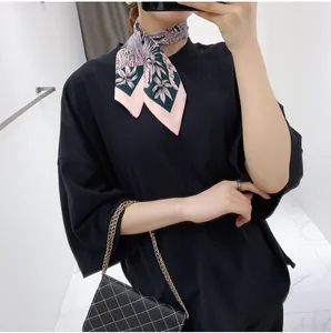 Detail of pink and green floral silk scarf styled as a neck tie with modern accessories